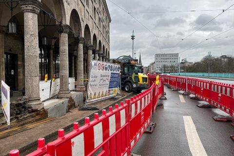 Bauarbeiten an den Arkaden der historischen Stadthalle in Mülheim; rote Absperrungen bilden einen alternativen Fußweg über einen Teil der Straße an der Mülheimer Schloßbrücke.
