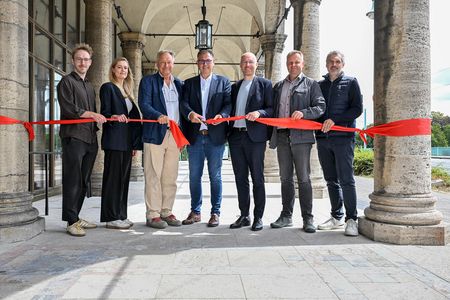 Die für die Arkaden-Sanierung Verantwortlichen stehen hinter einem roten Band, das an den Säulen der Stadthalle Mülheim angebracht ist, und lächeln in die Kamera, während der MST-Geschäftsführer das Band zerschneidet.
