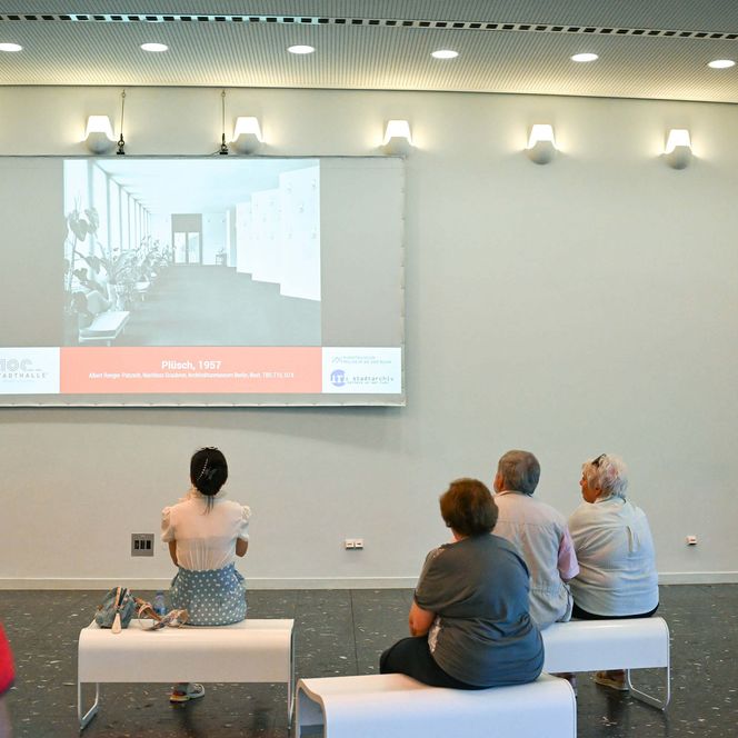Auf einer Leinwand sind historische Fotos der Stadthalle Mülheim zu sehen.